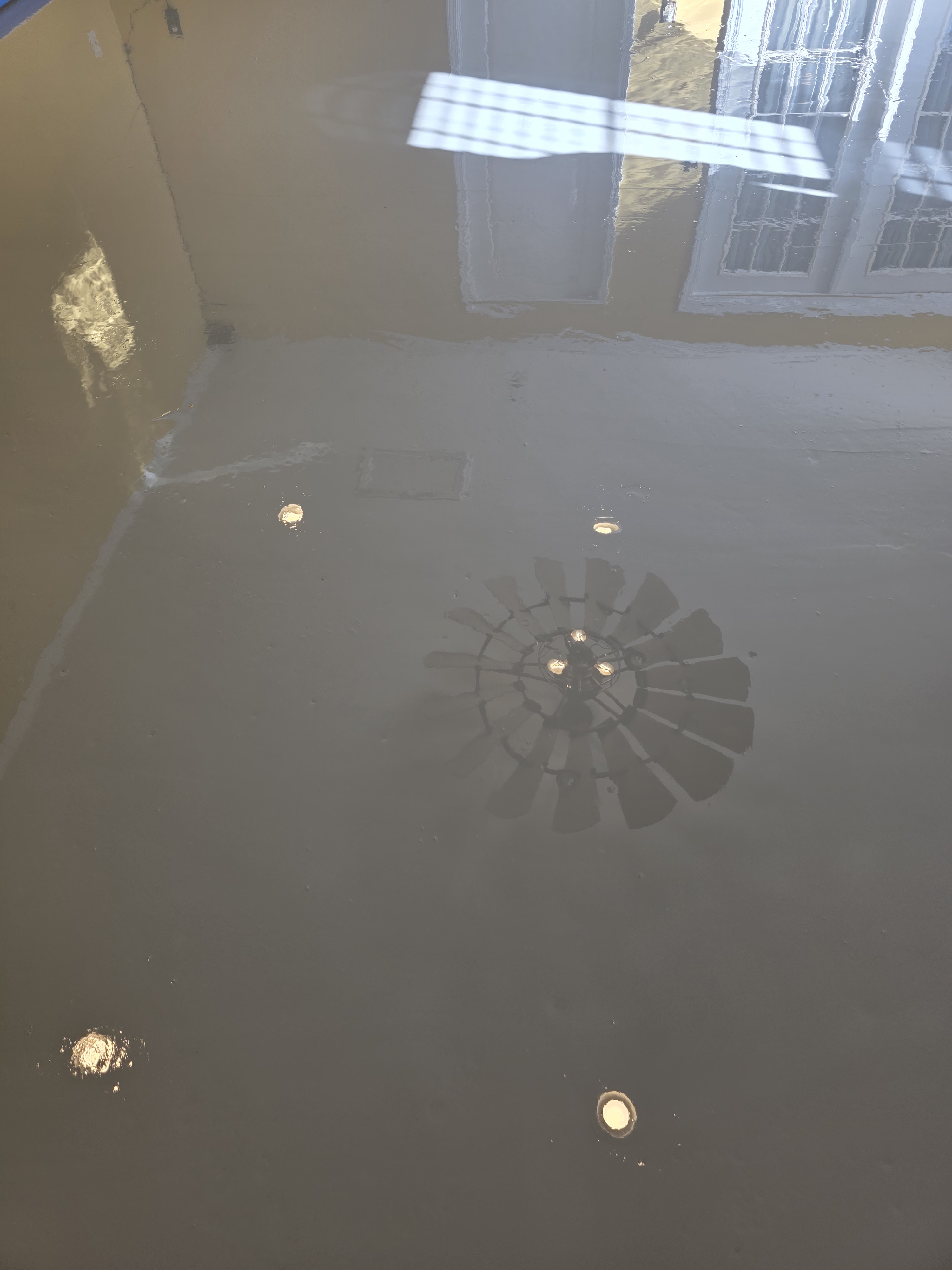 Freshly coated gray floor reflecting the ceiling fan and lights